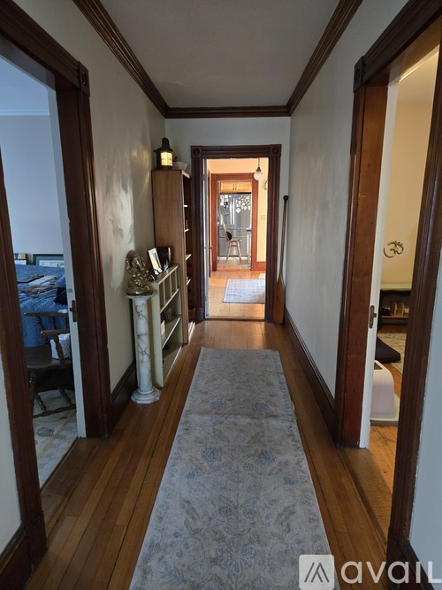 A hallway with a rug and a white column.