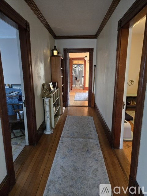 A hallway with a rug and a white column.