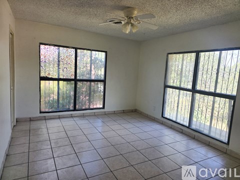 A room with a ceiling fan and two windows.