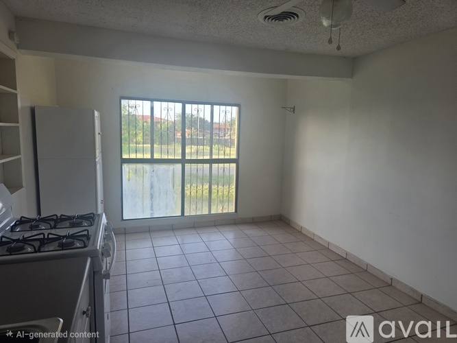 A kitchen with a gas stove and a window overlooking a fence.