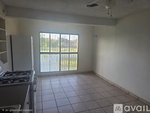 A kitchen with a gas stove and a window overlooking a fence.