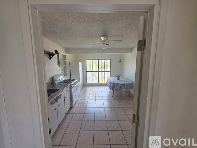 A kitchen with white cabinets and a table with a round tablecloth on it.