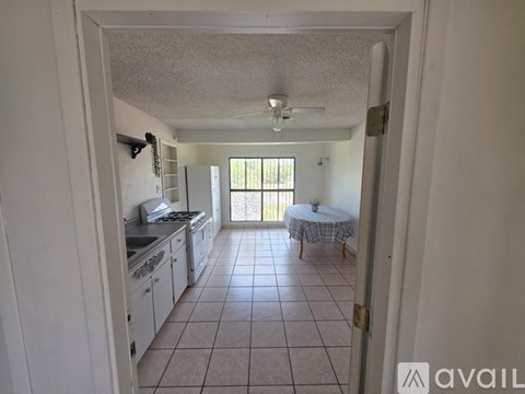 A kitchen with white cabinets and a table with a round tablecloth on it.
