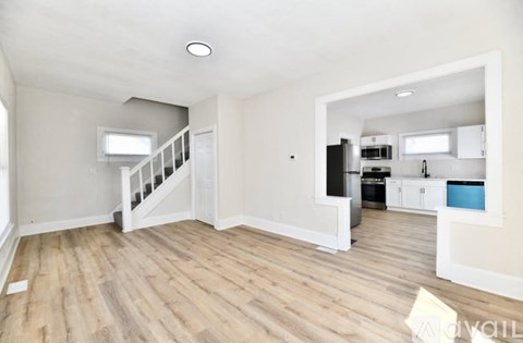 A spacious room with wooden flooring and a staircase leading to another room.