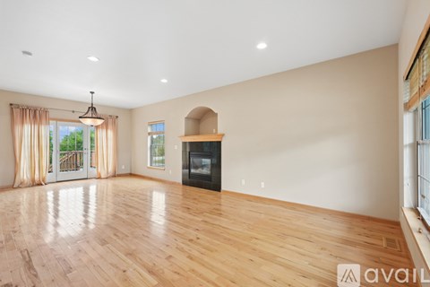 A spacious living room with wood flooring and a fireplace.