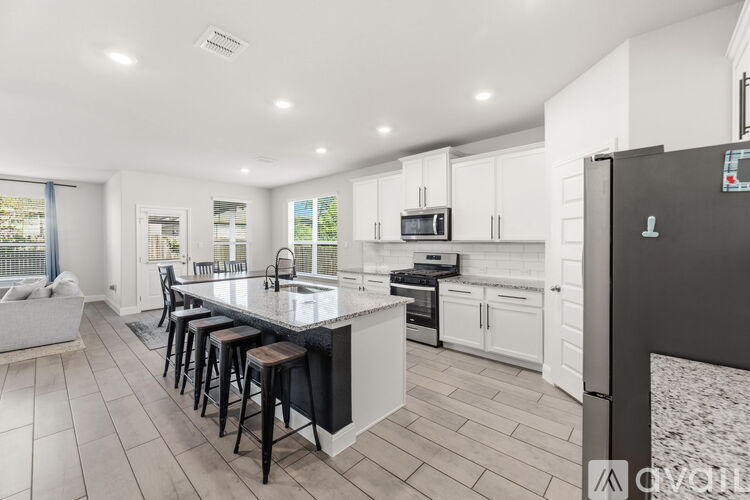 A kitchen with white cabinets and a black fridge.