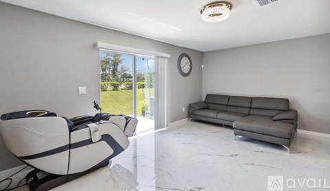 A modern living room with a grey sofa and a white and black gaming chair.