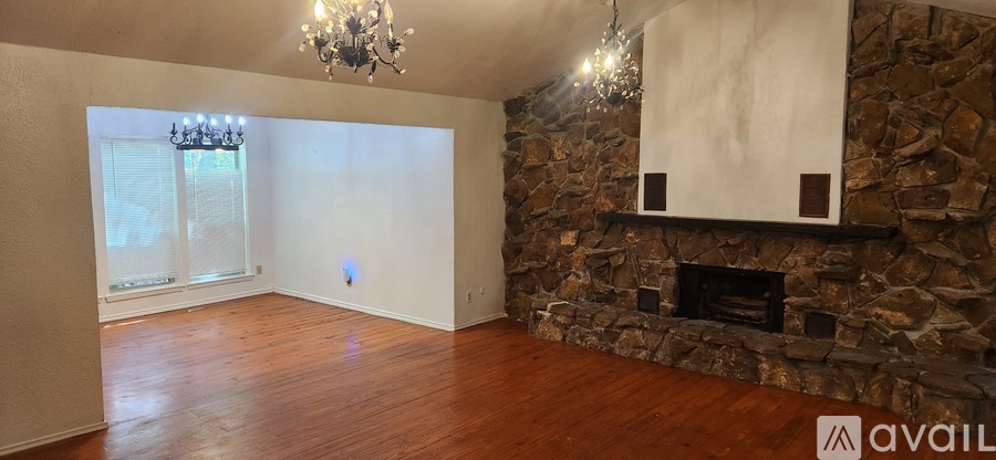 A room with a stone fireplace and a chandelier.