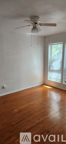 A room with a ceiling fan and wooden flooring.