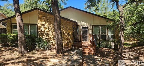A house with a stone wall and trees around it.