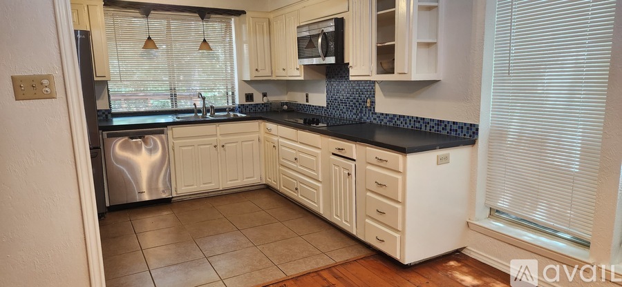 A kitchen with white cabinets and a black countertop.