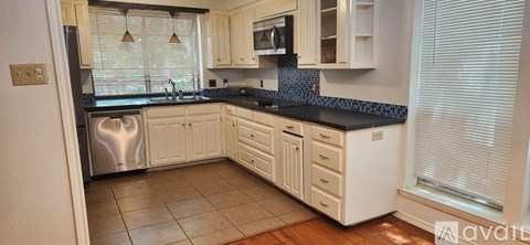 A kitchen with white cabinets and a black countertop.