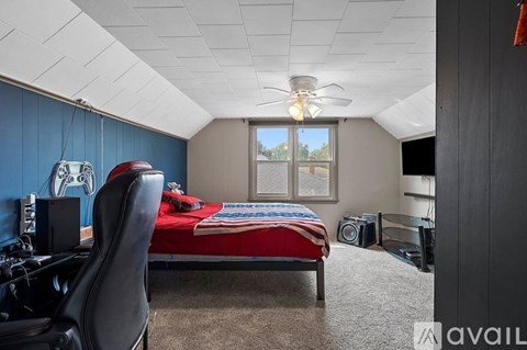 A room with a bed, desk, and ceiling fan.