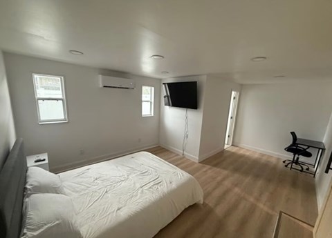 A bedroom with a bed, chair, and television.