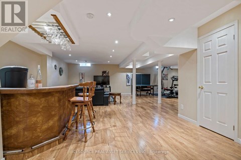 A well-lit, spacious living room with a bar area and a dining area in the background.