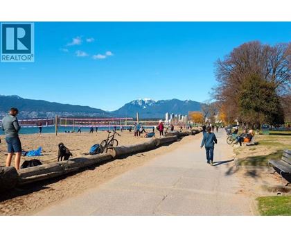 A woman is walking her dog on a sunny day at the beach.