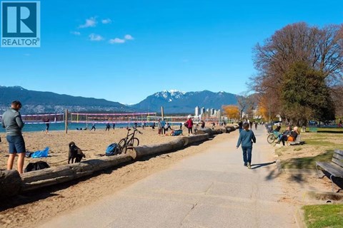 A woman is walking her dog on a sunny day at the beach.