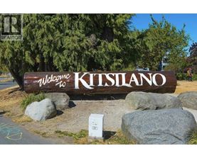 A wooden sign that says "Welcome to Kitsilano" is in front of some trees.