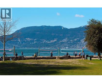 A park with people walking and a mountain in the background.