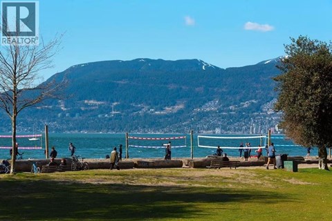 A park with people walking and a mountain in the background.