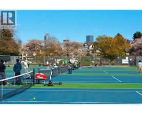 A tennis court with people playing tennis and a Whole Foods sign in the background.