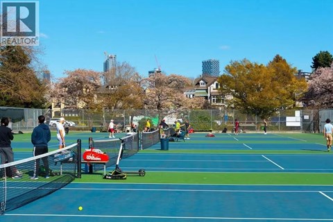 A tennis court with people playing tennis and a Whole Foods sign in the background.