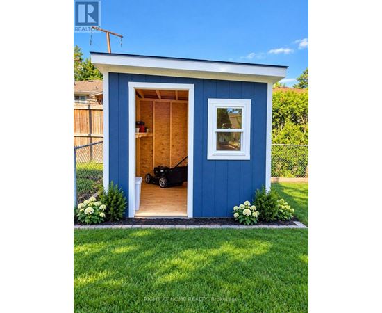 A blue shed with a black lawn mower inside.