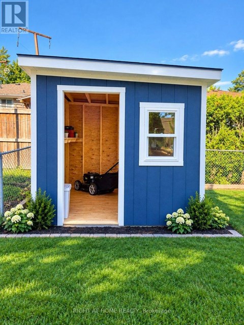 A blue shed with a black lawn mower inside.