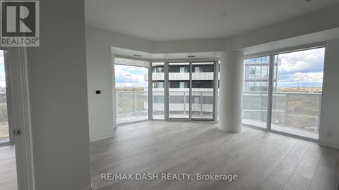 A spacious room with a view of the cityscape through large windows.