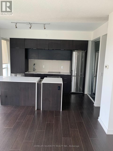 A modern kitchen with dark wood floors and white countertops.