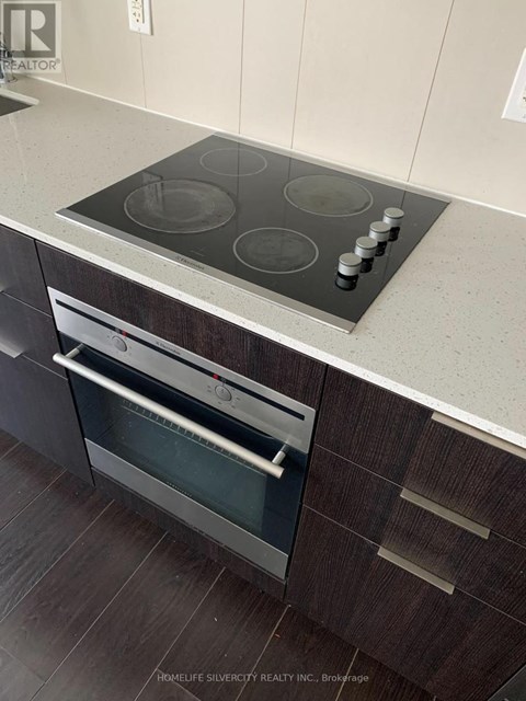 A modern kitchen with a stainless steel oven and a wooden cabinet.