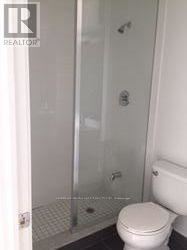 A white toilet in a small bathroom with a glass shower door.