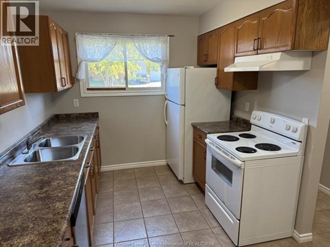 A kitchen with a white stove top oven and a window with a view of trees.