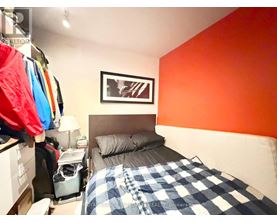 A bedroom with a bed, a nightstand, and a picture on the wall.