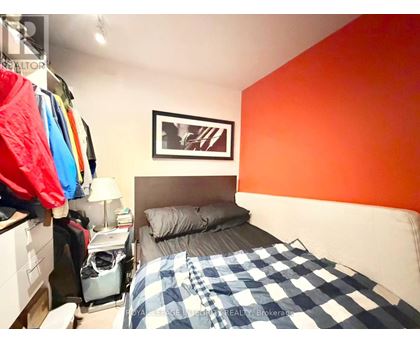 A bedroom with a bed, a nightstand, and a picture on the wall.