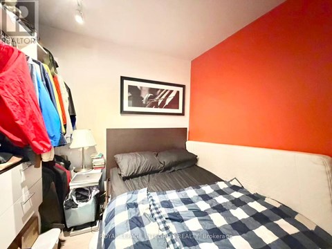 A bedroom with a bed, a nightstand, and a picture on the wall.