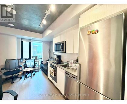 A kitchen with a refrigerator, microwave, and a dining table with chairs.
