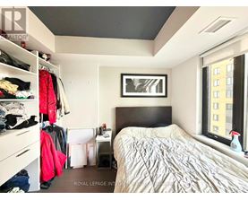 A bedroom with a bed, a window, and a closet with clothes.