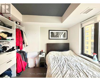 A bedroom with a bed, a window, and a closet with clothes.