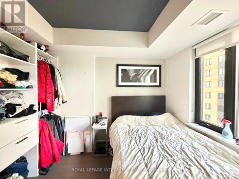 A bedroom with a bed, a window, and a closet with clothes.