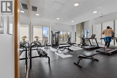 A man is working out on a treadmill in a spacious gym with various exercise equipment.