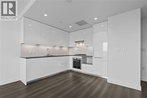 A modern kitchen with white cabinets and a wooden floor.