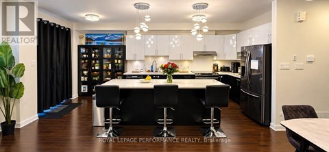 A modern kitchen with black bar stools and a wooden floor.
