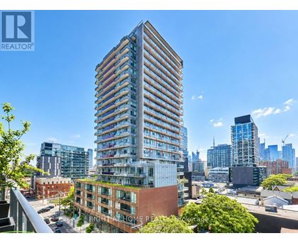 A tall building with many windows is in the foreground of a cityscape.