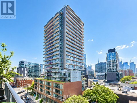 A tall building with many windows is in the foreground of a cityscape.