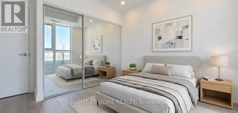A bedroom with a large bed, a nightstand, and a painting on the wall.