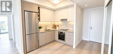 A kitchen with a refrigerator, sink, and countertop.