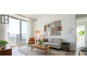 A living room with a grey couch, a brown armchair, a coffee table, and a large window with a view of the city.