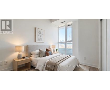 A bedroom with a large bed, a nightstand with a lamp, and a framed picture on the wall.