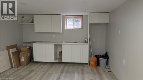 A room with a window, cabinets, and a broom.
